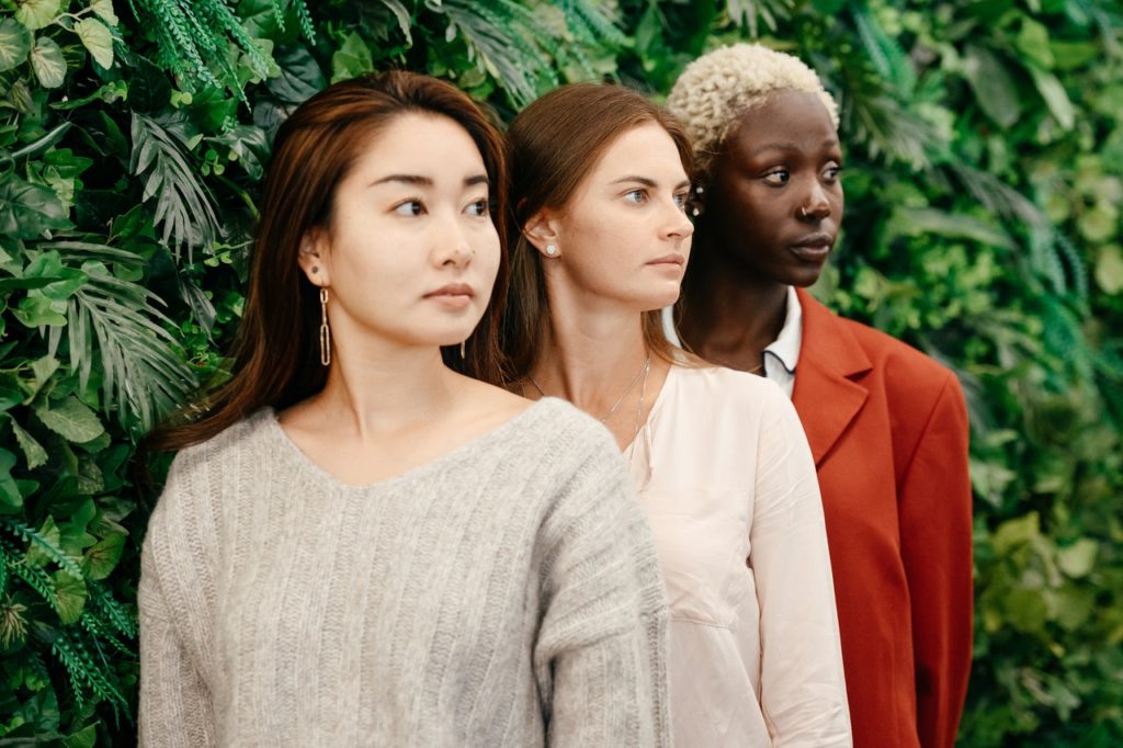 Three Women standing against a living wall.